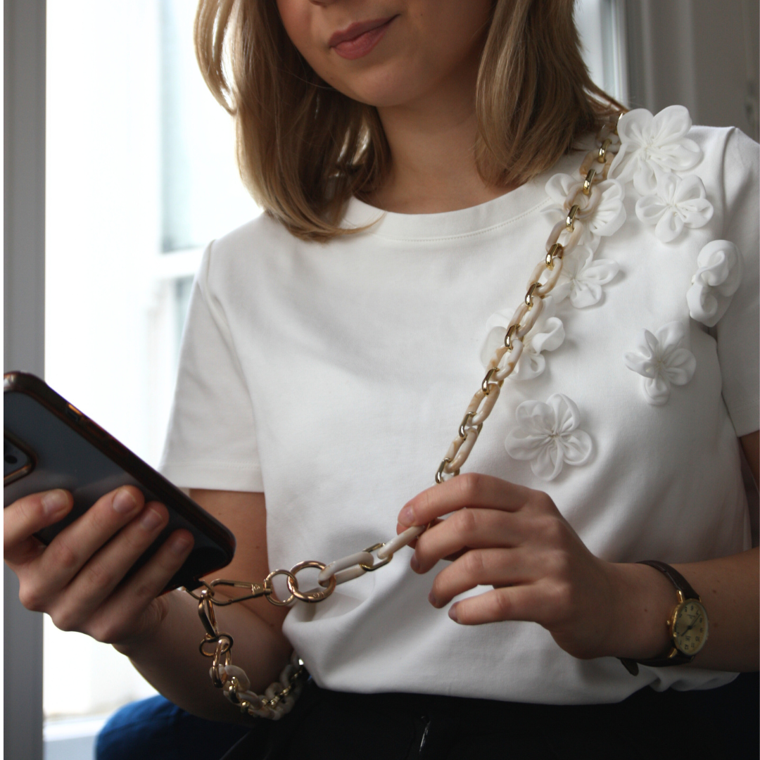 Blond girl wearing a white crossbody phone strap.