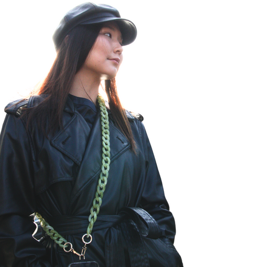 Asian looking girl posing and wearing jade green coloured crossbody phone strap. Front side.