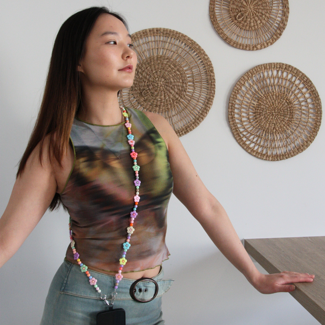 Asian girl posing while wearing multicoloured beads crossbody phone strap.